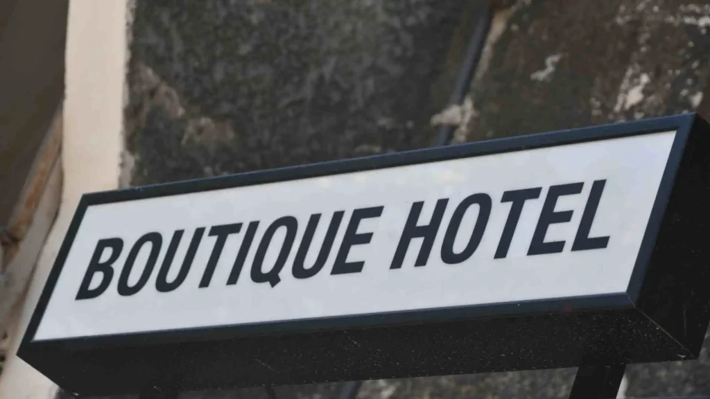 Letrero blanco y negro con la inscripción 'BOUTIQUE HOTEL' contra una pared, indicando un alojamiento exclusivo.